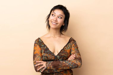 Hintli kadın bej arka planda izole edilmiş gülümserken yukarı bakıyor