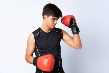 İzole edilmiş mavi arka planda boks eldivenli bir sporcu.