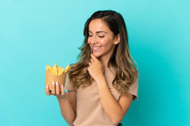 Kızarmış cipsleri izole edilmiş arka planda tutan genç bir kadın yana bakıyor ve gülümsüyor.