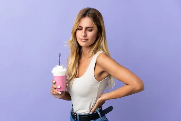 年轻的金发乌拉圭女人 有草莓奶昔 背景是紫色 背痛难忍 因为她付出了努力 — 图库照片