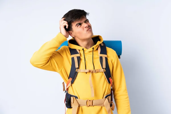 Молодий Альпініст Великим Рюкзаком Над Ізольованим Синім Тлом Має Сумніви — стокове фото