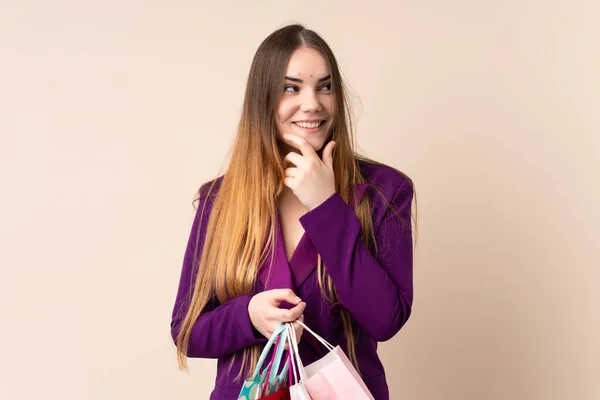 Jonge Blanke Vrouw Geïsoleerd Beige Achtergrond Met Winkeltassen Denken — Stockfoto