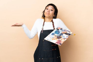 Soyutlanmış arka planda palet tutan genç bir sanatçı, kafa karıştırıcı yüz ifadesi ile ilgili şüpheleri var.