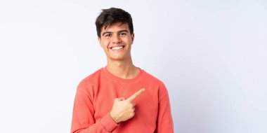 Soyutlanmış mavi arkaplan üzerinde yakışıklı bir adam bir ürün sunmak için kenarı işaret ediyor