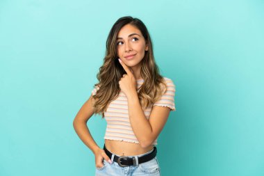 Genç bir kadın mavi arka planda, gülümserken yukarı bakıyor.