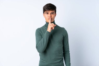 Izole mavi arka plan üzerinde yakışıklı adam ağzına parmak koyarak sessizlik jest bir işareti gösteren