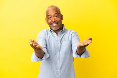 Küba Senior sarı arka planda izole edilmiş sunar ve davet edilir.