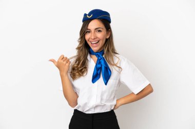 İzole edilmiş beyaz arka planda uçak hostesi bir ürünü sunmak için kenarı işaret ediyor.