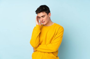 Beyaz, yakışıklı, mor arka planda başağrısı olan genç bir adam.