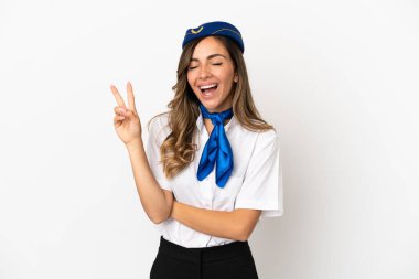 İzole edilmiş beyaz arka planda gülümseyen ve zafer işareti gösteren uçak hostesi.