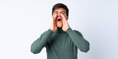 Yakışıklı adam mavi arka planda bağırıyor ve bir şey duyuruyor.