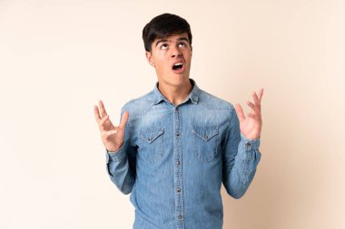 Tecrit edilmiş bej arka planda yakışıklı bir adam stresli