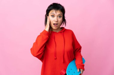 Genç Uruguaylı kadın pembe arka planda paten kayıyor ve sürpriz jest yapıyor.