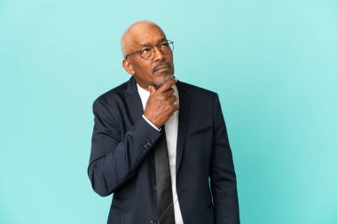 İşletme son sınıf öğrencisi mavi arka planda izole edilmiş. Şüpheleri ve düşünceleri var.