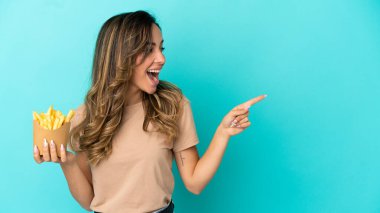 Kızarmış cipsleri izole edilmiş arka planda tutan genç bir kadın parmak göstererek bir ürün sunuyor.