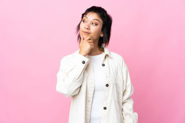 Genç Uruguaylı kadın soyutlanmış pembe arka plan ve yukarı bakıyor