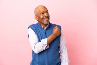 Kübalı son sınıf öğrencisi pembe arka planda zaferi kutluyor.