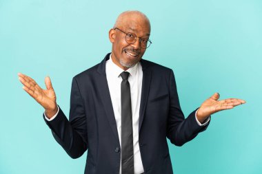 İşletme son sınıf öğrencisi, mavi arka planda şok olmuş yüz ifadesiyle izole edilmiş.