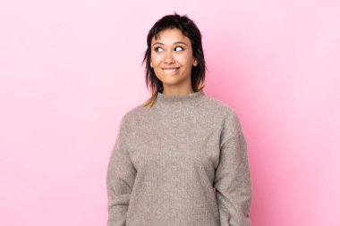 Genç Uruguaylı kadın soyutlanmış pembe arka planı araştırırken kuşkuları var.