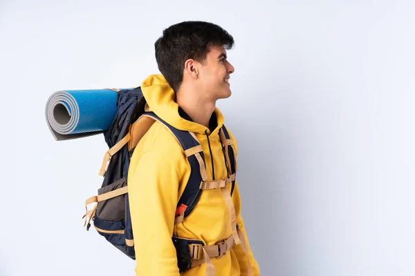 Joven Montañero Con Una Gran Mochila Sobre Fondo Azul Aislado —  Fotos de Stock