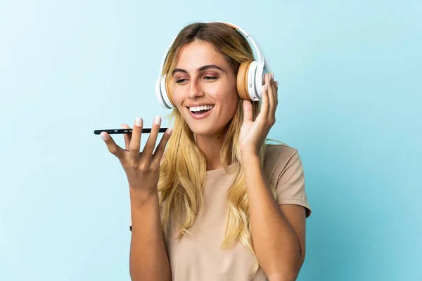 Jeune Uruguayenne Blonde Isolée Sur Fond Bleu Écoutant Musique Avec — Photo