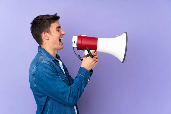 Tiener Kaukasische Knappe Man Geïsoleerd Paarse Achtergrond Schreeuwen Door Een — Stockfoto