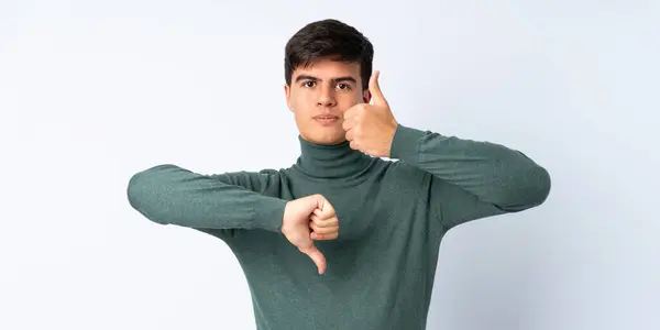 Homem Bonito Sobre Fundo Azul Isolado Fazendo Bom Mau Sinal — Fotografia de Stock