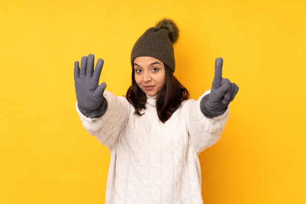 年轻女子头戴冬帽 黄底孤零零的 手指数六根 — 图库照片