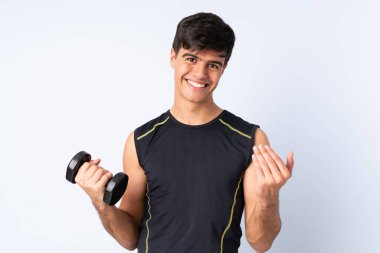 Sport man making weightlifting over isolated blue background inviting to come with hand. Happy that you came