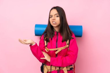 Pembe arka planda büyük bir sırt çantası olan genç dağcı kız bir şeyi anlamadığı için mutsuz.