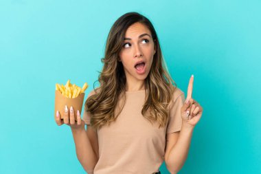 Kızarmış cipsleri izole edilmiş arka planda tutan genç bir kadın bir fikrin suçluyu işaret ettiğini düşünüyor.