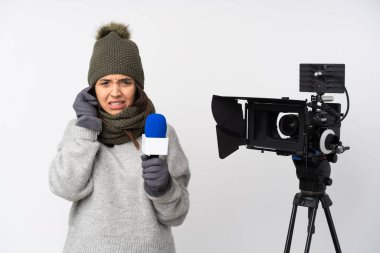 Elinde mikrofon tutan ve izole edilmiş beyaz arka planda haber sunan gazeteci kadın hayal kırıklığına uğramış ve kulaklarını tıkamış.