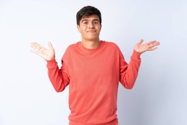 Soyutlanmış mavi arkaplan üzerinde yakışıklı bir adam ellerini kaldırırken şüphe duyuyor