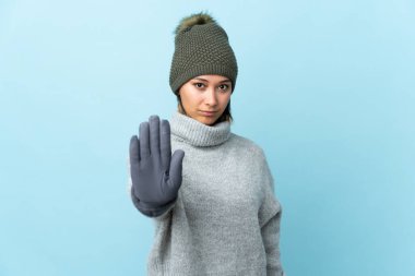 Mavi arka planda izole edilmiş küçük Uruguaylı kız eliyle durdurma hareketi yapıyor.