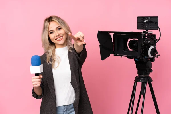 レポーター女性を保持マイクと報告ニュースの上に隔離されたピンクの背景点指であなたに笑顔 — ストック写真