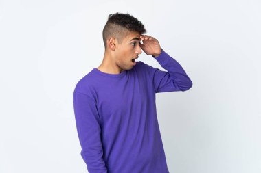 Genç Brezilyalı bir adam beyaz arka planda izole edilmiş. Sürpriz bir ifadeyle yan tarafa bakıyor.