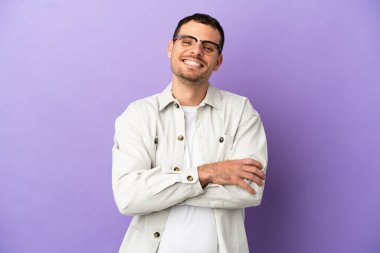 Mor arka planda izole edilmiş Brezilyalı adam kollarını ön konumda çapraz tutuyor.