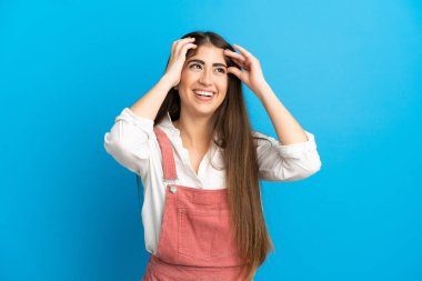 Mavi arka planda izole edilmiş genç beyaz kadın gülüyor.