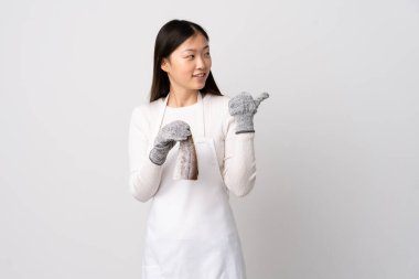 Çinli balıkçı önlük takıyor ve çiğ balığı izole edilmiş beyaz arka planda tutuyor.