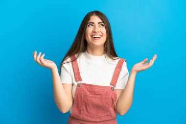 Mavi arka planda izole edilmiş genç beyaz kadın çok gülümsüyor.