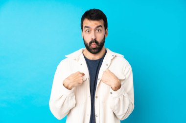 Beyaz kadife ceketli genç ve yakışıklı bir adam izole edilmiş mavi arka planda kendini işaret ediyor.