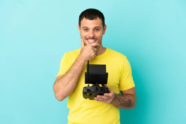 İzole edilmiş mavi arka plan üzerinde uzaktan kumanda tutan Brezilyalı bir adam