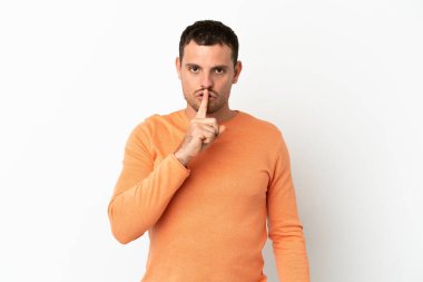 İzole edilmiş beyaz arka plan üzerinde Brezilyalı bir adam sessizlik işareti gösteriyor. Parmağını ağzına sokuyor.
