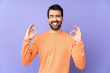 İzole edilmiş mor arka planda beyaz, yakışıklı bir adam parmaklarıyla 