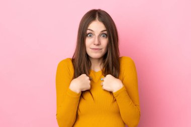 Pembe arka planda izole edilmiş genç beyaz kadın kendini işaret ediyor.