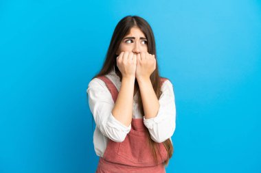Mavi arka planda izole edilmiş beyaz bir kadın gergin ve korkmuş bir şekilde elleriyle suni teneffüs yapıyor.