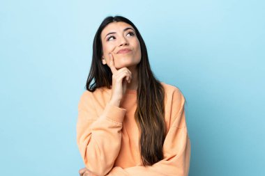 Genç esmer kız soyutlanmış mavi arka plan araştırırken kuşkuları var.