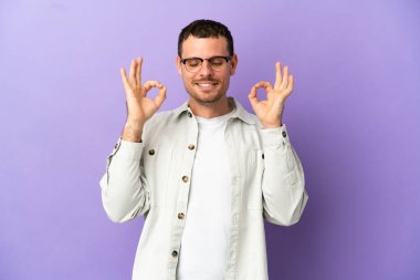 Brezilyalı erkek Zen pozunda mor arka planda izole edilmiş