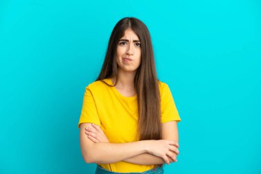 Mutsuz bir ifadeyle mavi arka planda izole edilmiş beyaz bir kadın.