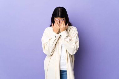 Genç esmer kadın, soyutlanmış mor arka plan, yorgun ve hasta bir ifade.